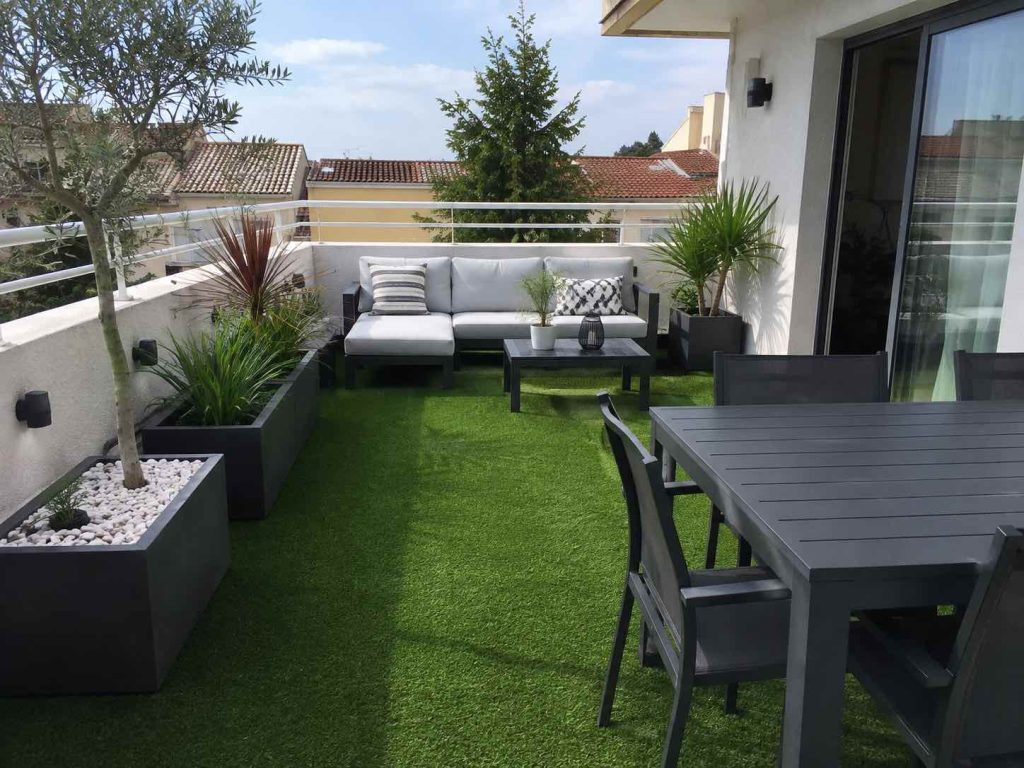Terrasse aménagée avec gazon synthétique, plantations, arrosage automatique et mobilier de jardin contemporain.